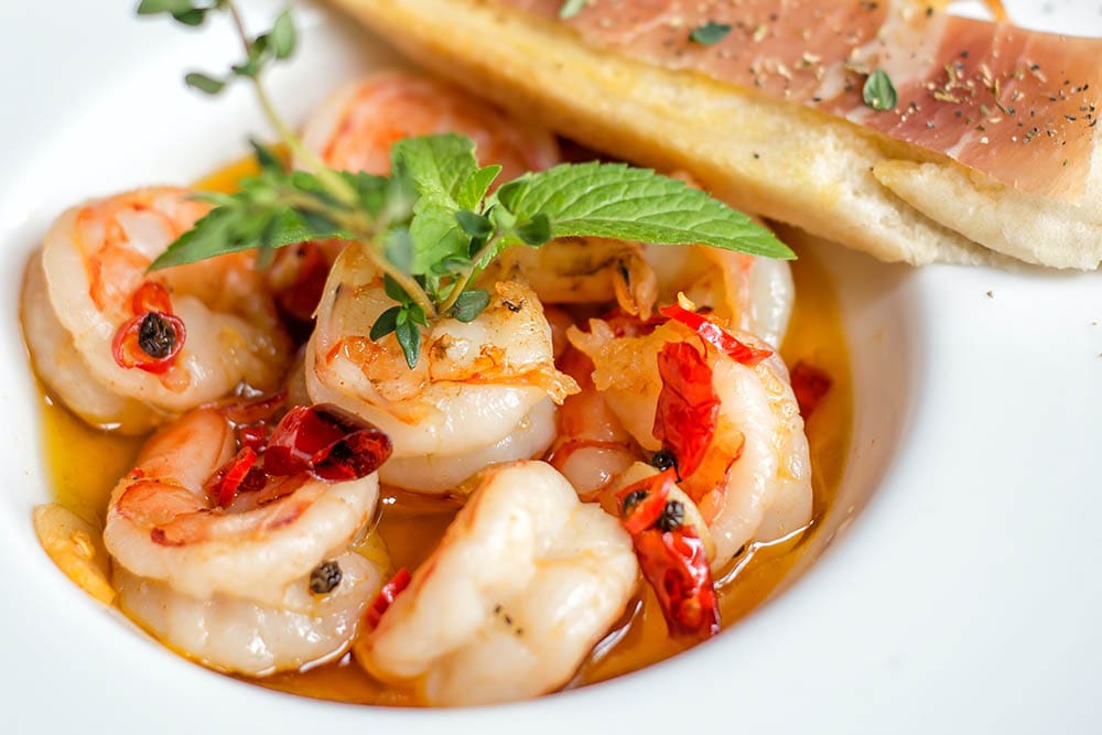 A plate of food with shrimp and herbs.