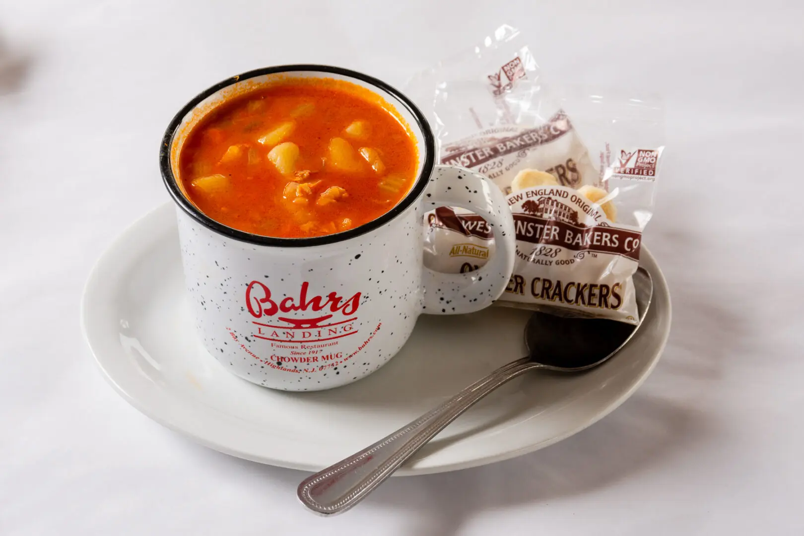 A bowl of soup and crackers on a plate.
