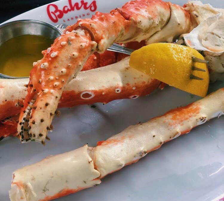 A plate of crab legs with lemon and dipping sauce.